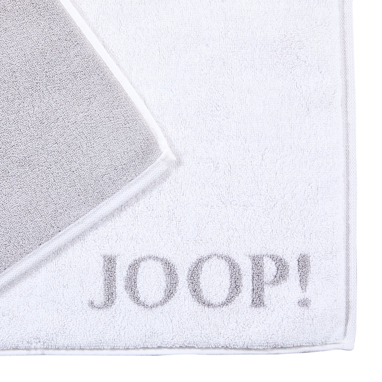 Weiße Badematte mit grauem Rand und dem Schriftzug 'JOOP!' in der Ecke, von oben fotografiert.