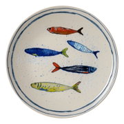 Runder cremefarbener Keramikteller mit blauem Doppelrand und fünf handgemalten, farbenfrohen Fischmotiven, in leichter Draufsicht dargestellt