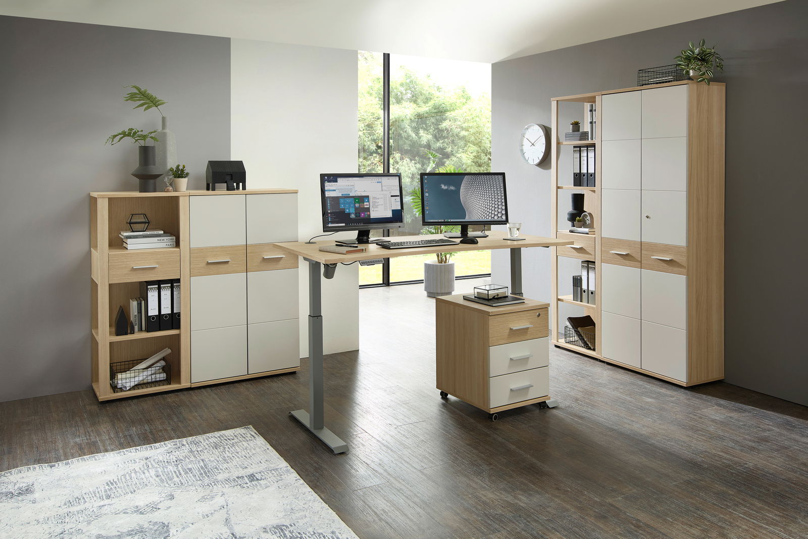 Moderner höhenverstellbarer Schreibtisch mit zwei Monitoren, umgeben von Aktenschränken und Regalen in einem hellen Büro mit Blick auf den Garten. Perspektive: Frontalansicht.