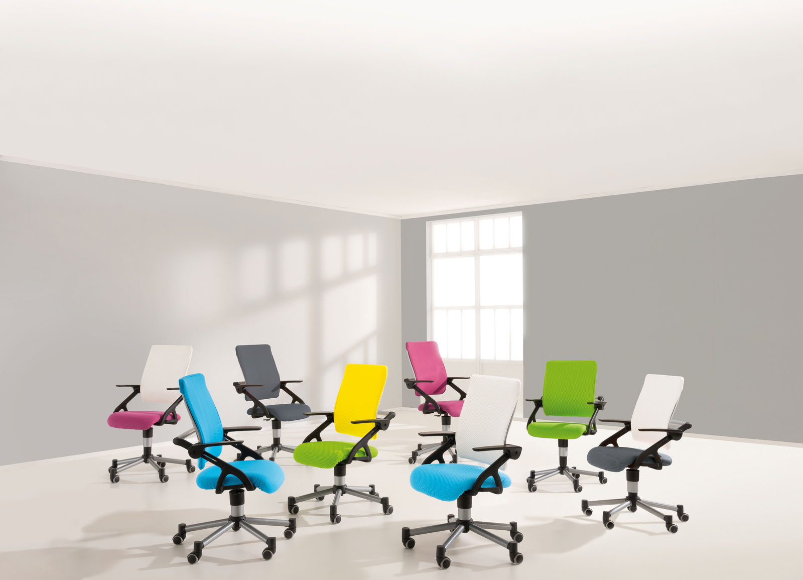 Paidi Jugenddrehstuhl TIO Eine Gruppe von bunten Jugenddrehstühlen in einem hellen Raum, aus einer leicht erhöhten Perspektive fotografiert.