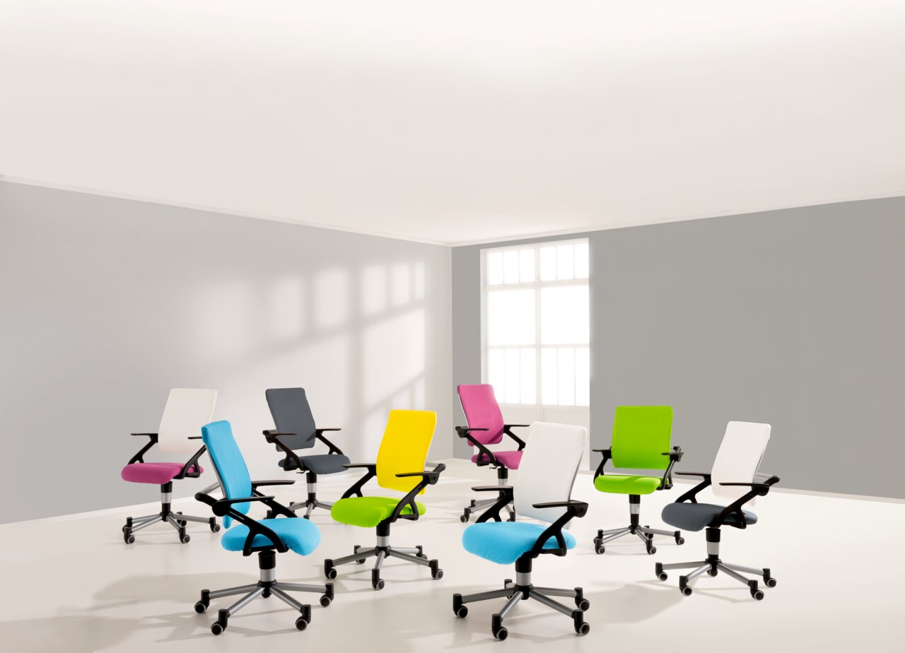 Eine Gruppe von bunten Jugenddrehstühlen in einem hellen Raum, aus einer leicht erhöhten Perspektive fotografiert.