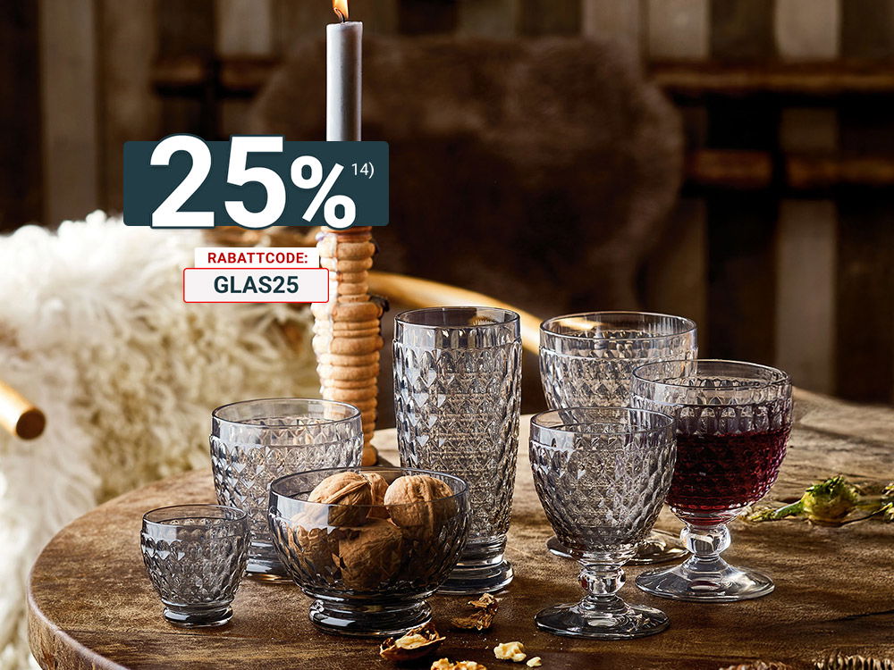 Rustikaler Holztisch mit dekorativen, facettierten Trinkgläsern, Nüssen und einer brennenden Kerze in gemütlicher Atmosphäre