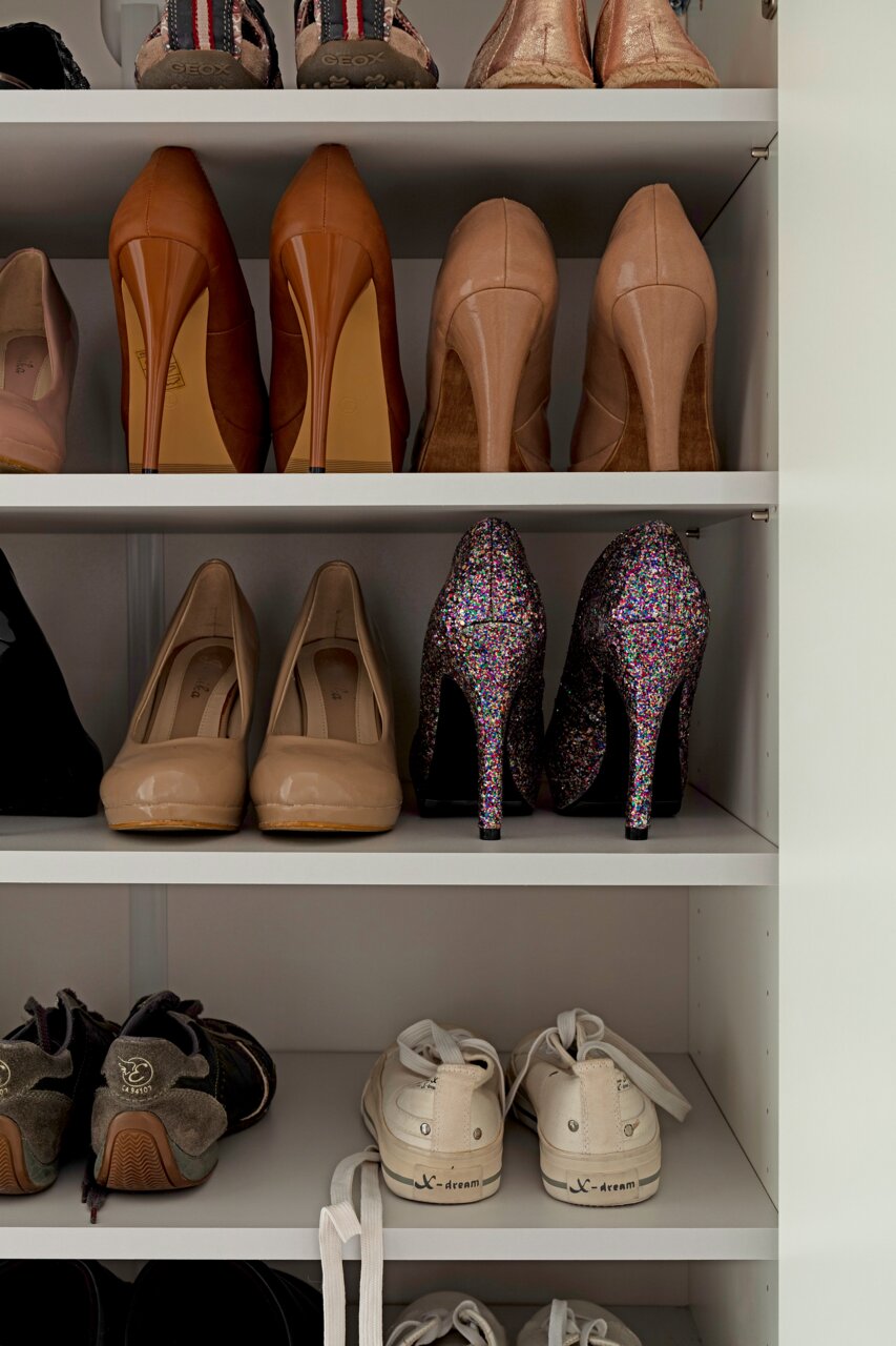 Schuhschrank mit verschiedenen Schuhen, darunter High Heels und Sneakers, aus der frontalen Perspektive.
