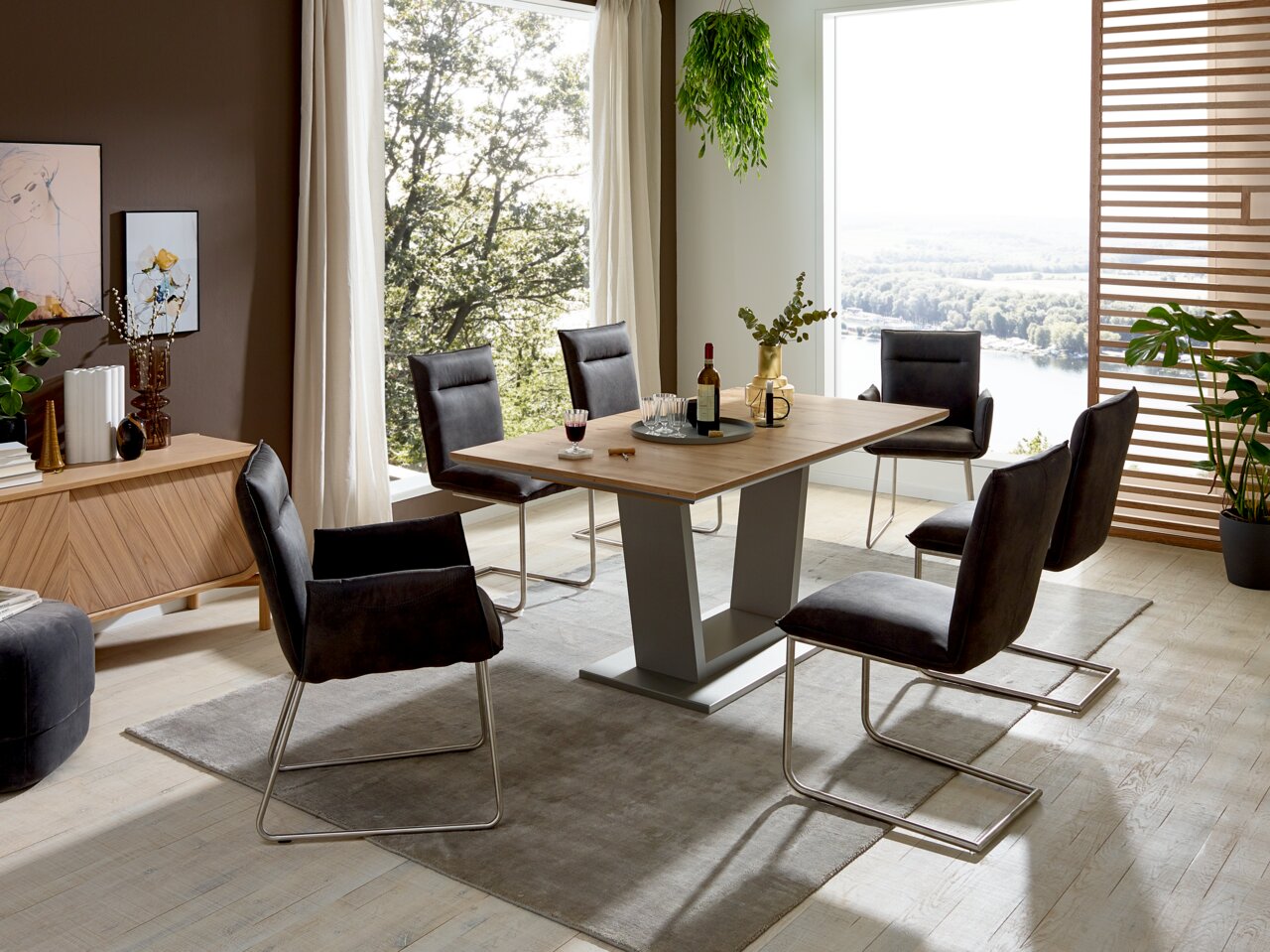 Valnatura Stuhl SCALA Moderner Essbereich mit einem rechteckigen Holztisch und sechs Freischwinger-Stühlen in einem hellen Raum mit großen Fenstern und Pflanzen. Perspektive: seitliche Ansicht.