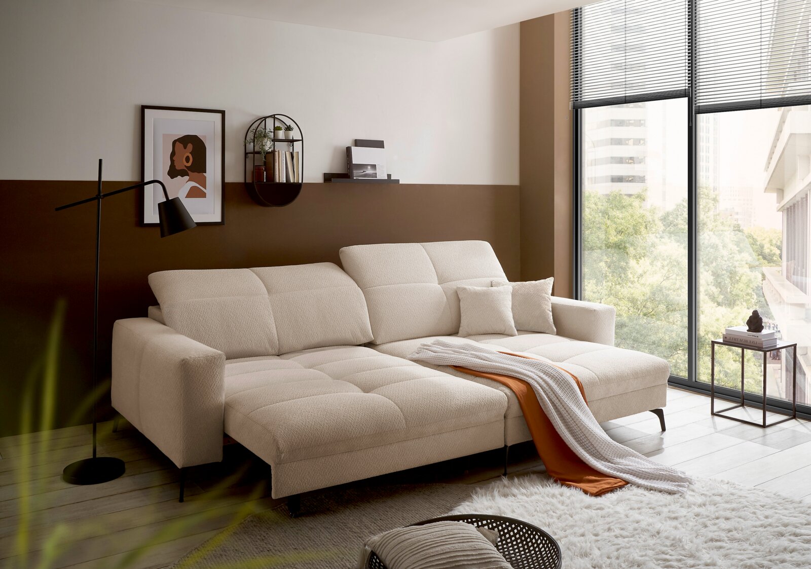 Modernes cremefarbenes Sofa mit zwei Chaiselongues und Kissen im Wohnzimmer, seitliche Vorderansicht von links mit großem Fenster im Hintergrund