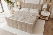 Beiges, gepolstertes Boxspringbett mit hohem, gestepptem Kopfteil und passender Bettbank, bezogen mit heller Bettwäsche in modernem Schlafzimmer, schräg von oben aus der linken Vorderperspektive fotografiert.