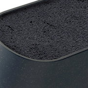Close-up van een donkere, ovaalvormige kattenbak met zwarte absorberende korrels, gefotografeerd schuin van boven (bovenaanzicht).