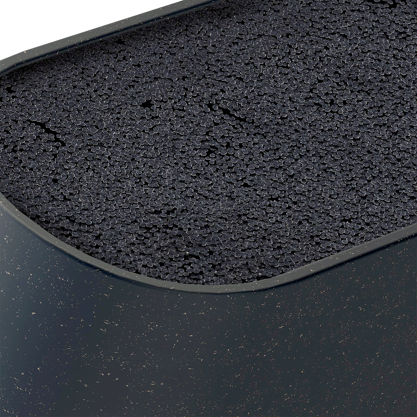 Close-up van een donkere, ovaalvormige kattenbak met zwarte absorberende korrels, gefotografeerd schuin van boven (bovenaanzicht).