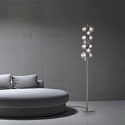 Moderne LED-Stehleuchte PURE POPOUT mit mehreren kugelförmigen Leuchten, seitliche Perspektive neben einem runden Sofa in einem minimalistischen Raum.