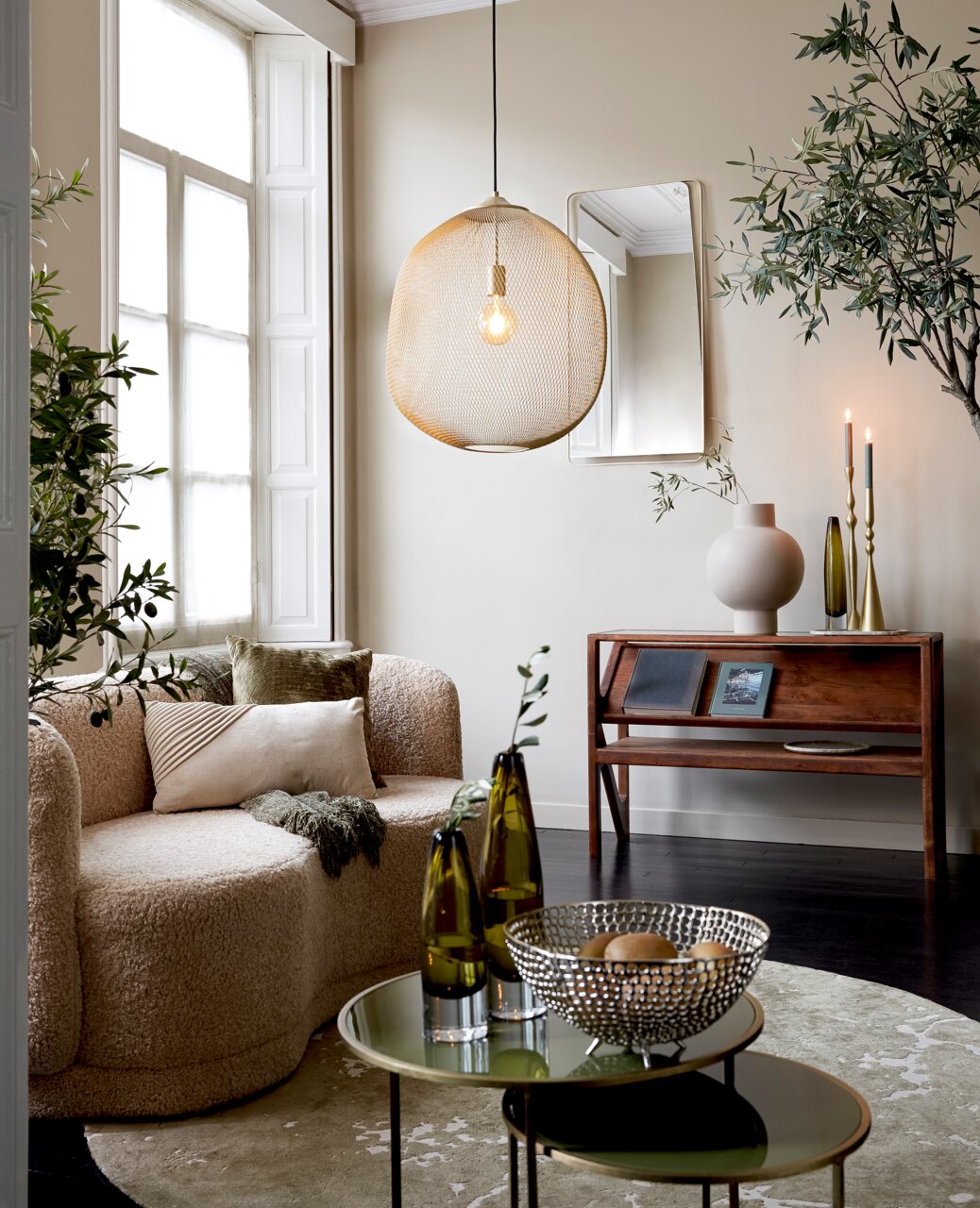 Moderne Hängeleuchte aus Metallgeflecht in einem stilvoll eingerichteten Wohnzimmer, seitliche Perspektive.
