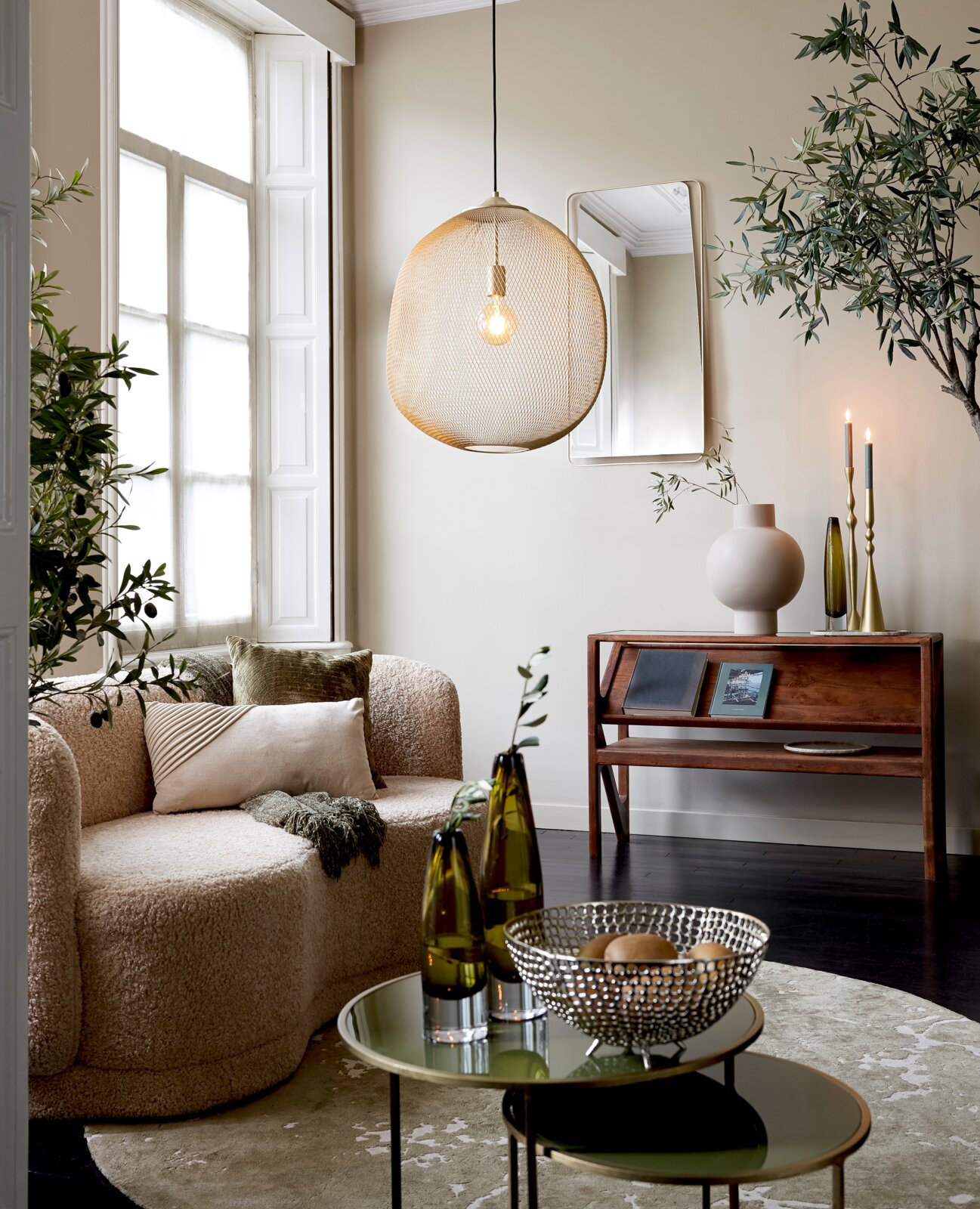 Moderne Hängeleuchte aus Metallgeflecht in einem stilvoll eingerichteten Wohnzimmer, seitliche Perspektive.