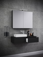 Modernes, wandhängendes Badezimmer-Waschplatz-Set mit schwarzem Unterschrank und weißem Aufsatzwaschbecken, darüber Spiegelschrank mit LED-Leuchte vor Betonwand, Frontansicht mit leichter Schrägperspektive von links.
