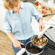 Frau in der Küche, die ein Vitavit Premium Set 4,5 l verwendet, um Muscheln und Gemüse zu kochen. Perspektive von oben.