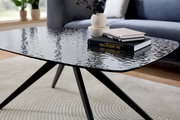 Moderner Couchtisch mit schwarzer, strukturierter Glasplatte und schlanken Metallbeinen, seitliche Perspektive.