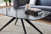 Moderner Couchtisch mit schwarzer, strukturierter Glasplatte und schlanken Metallbeinen, seitliche Perspektive.