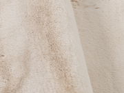 Nahaufnahme eines weichen, beigen Fellteppichs mit flauschiger Textur.