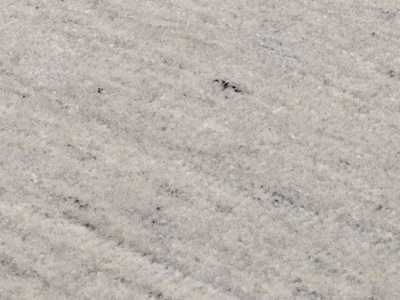 Nahaufnahme eines hellgrauen Wollteppichs mit feiner Textur