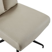 Close-up van een beige stoelzitting met een zwart metalen frame, gezien van bovenaf.