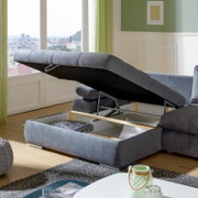 Grijze hoekbank met opbergruimte, open, in een moderne woonkamer met uitzicht op de stad.