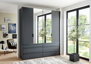 Moderner, grauer viertüriger Drehtürenschrank mit Spiegeltüren, in einem hellen Raum mit großen Fenstern, aus der Frontalperspektive betrachtet.