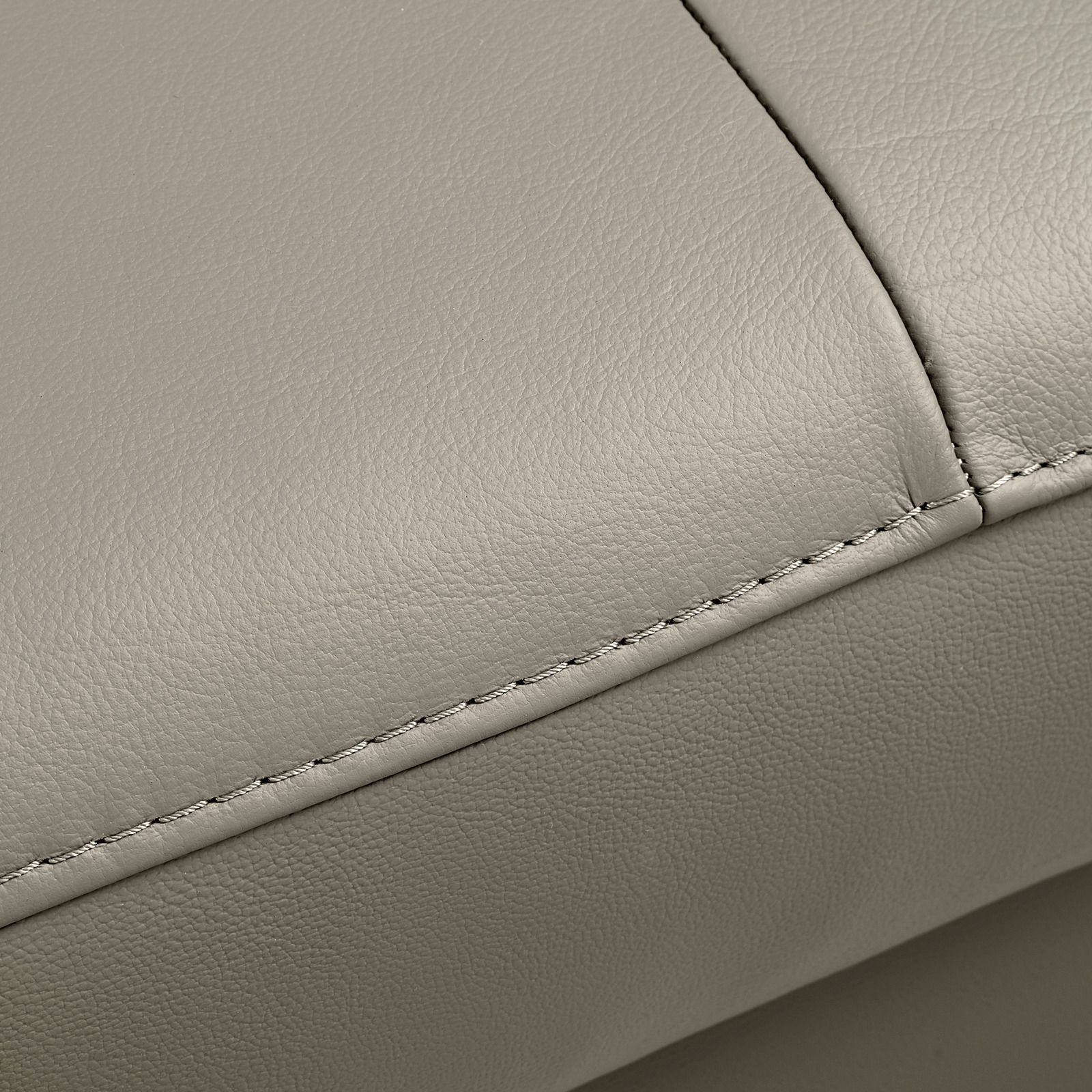 Nahaufnahme der Naht eines hellgrauen Ledersofas, Perspektive von oben