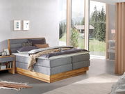 Modernes Boxspringbett in einem hellen Schlafzimmer mit großen Fenstern, seitliche Perspektive
