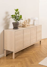 Holz-Sideboard mit vier Türen, dekoriert mit einer Pflanze, Kerzenhalter und Lampe, seitliche Perspektive