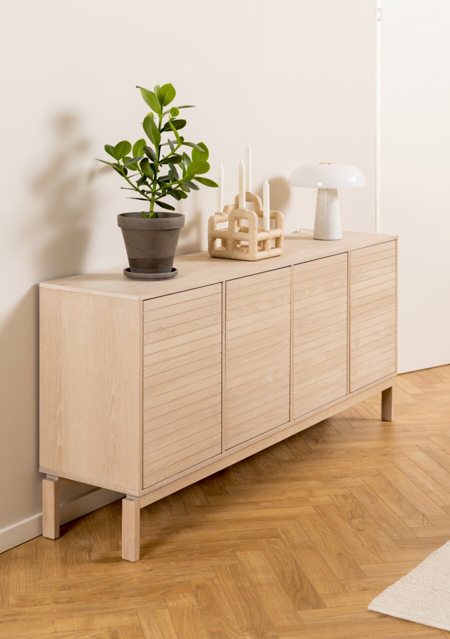 Houten dressoir met vier deuren, versierd met een plant, kandelaars en een lamp, zijaanzicht