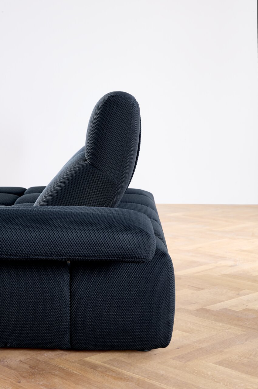 Zijaanzicht van een moderne, donkergrijze hoekbank met verstelbare rugleuning op een houten vloer.