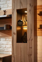 Detailansicht einer Wohnwand mit Holzoptik, beleuchtetem Regal und dekorativen Gläsern und Vasen.