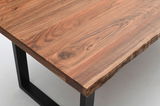 Nahaufnahme eines Esstisches mit natürlicher Holzmaserung und schwarzen Metallbeinen, aus der Perspektive von oben.