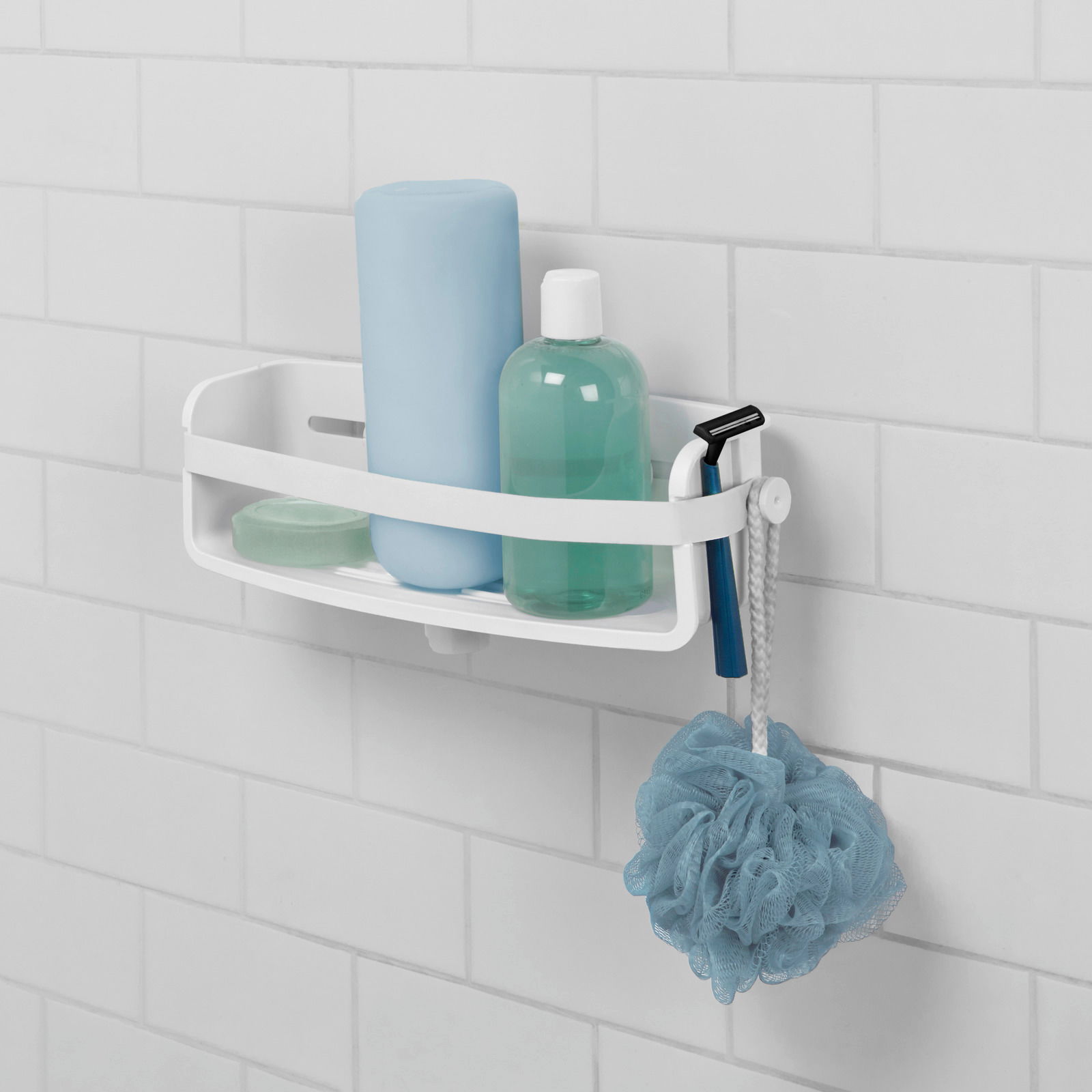 Weißes Flex Regal mit Gel Lock an einer gefliesten Badezimmerwand, gefüllt mit Duschutensilien wie Shampoo, Seife und einem Rasierer, seitliche Perspektive.