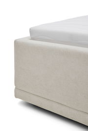 Nahaufnahme eines Polsterbettgestells in cremefarbener Textur, seitliche Perspektive