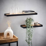 Zwei moderne Wandboards aus Holz und Metall, dekoriert mit Gläsern, Büchern und einer Pflanze, an einer hellen Wand montiert. Perspektive von vorne.