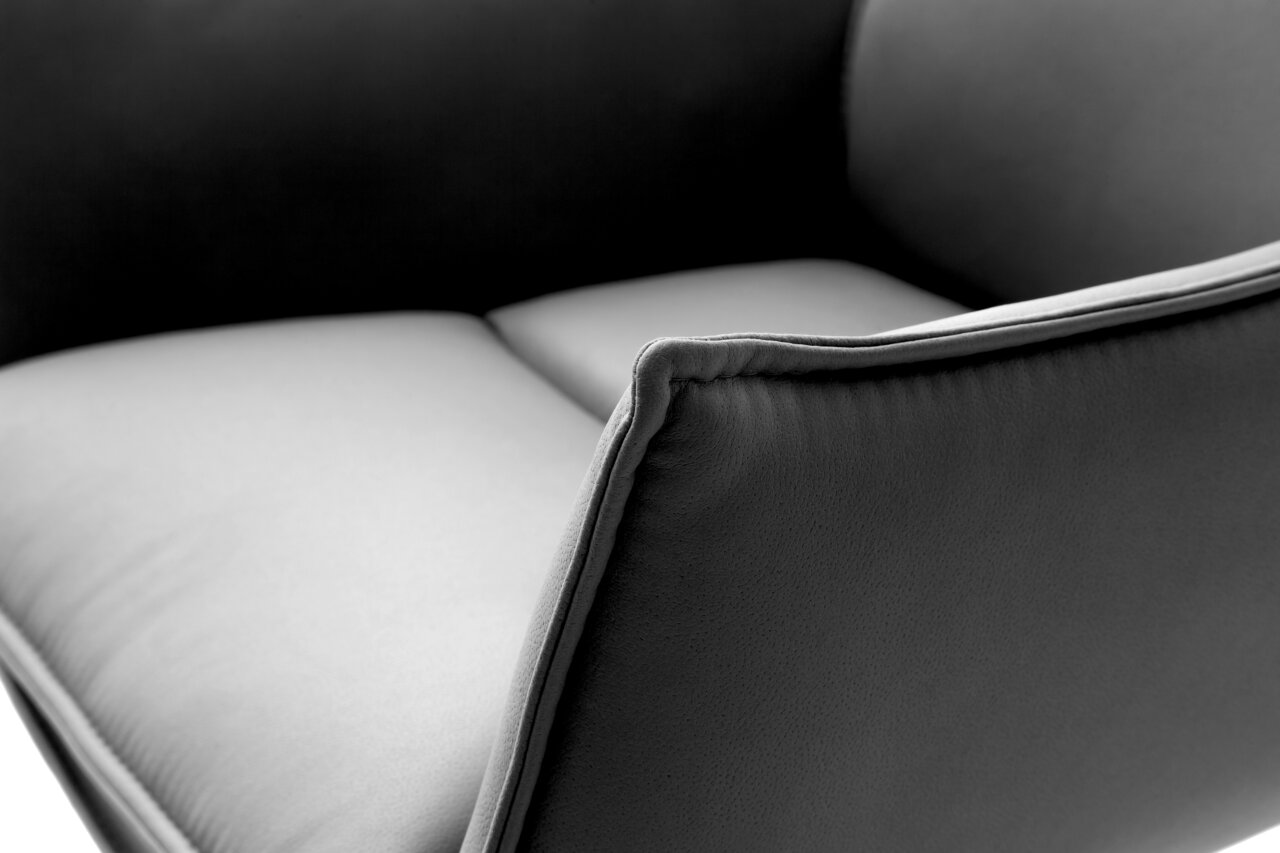 Nahaufnahme eines modernen Sessels in dunklem Grau mit weicher Polsterung, seitliche Perspektive.