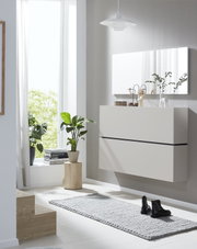 Weißer, wandhängender Schuhschrank mit zwei grifflosen Klappen, aus leicht seitlicher Frontalperspektive in einem hellen, modern eingerichteten Flur