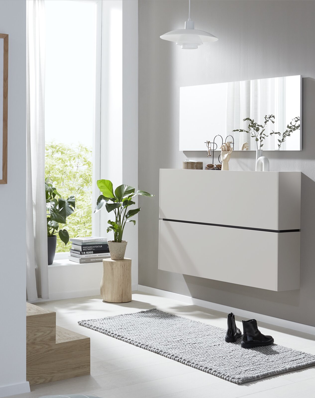 Weißer, wandhängender Schuhschrank mit zwei grifflosen Klappen, aus leicht seitlicher Frontalperspektive in einem hellen, modern eingerichteten Flur