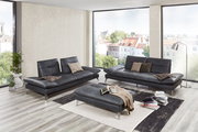 Modernes Wohnzimmer mit zwei dunkelgrauen 2,5-sitzigen Sofas und einem passenden Hocker, umgeben von großen Fenstern mit Stadtblick, aus der Perspektive von vorne.