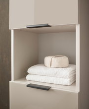 Hoge kast met open plank, gevuld met witte handdoeken en een opgevouwen doek, zijaanzicht