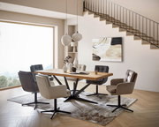 Moderner Essbereich mit einem großen Holztisch und sechs gepolsterten Armlehnstühlen in verschiedenen Farben, seitliche Perspektive.