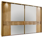 Moderner Schwebetürenschrank in Holzoptik mit zwei großen Spiegel-Schiebetüren, mittigem horizontalen Zierband und integrierter LED-Beleuchtung oben, frontal in leichter Perspektive von links fotografiert