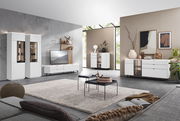 Moderne Wohnzimmermöbel in einem hellen Raum mit großen Fenstern, bestehend aus weißen Vitrinen, Sideboards und einem TV-Lowboard. Perspektive von der Sofaecke aus.
