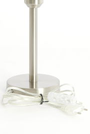 Nahaufnahme eines silbernen Lampenfußes mit rundem Sockel und transparentem Kabel mit Schalter, seitliche Perspektive.