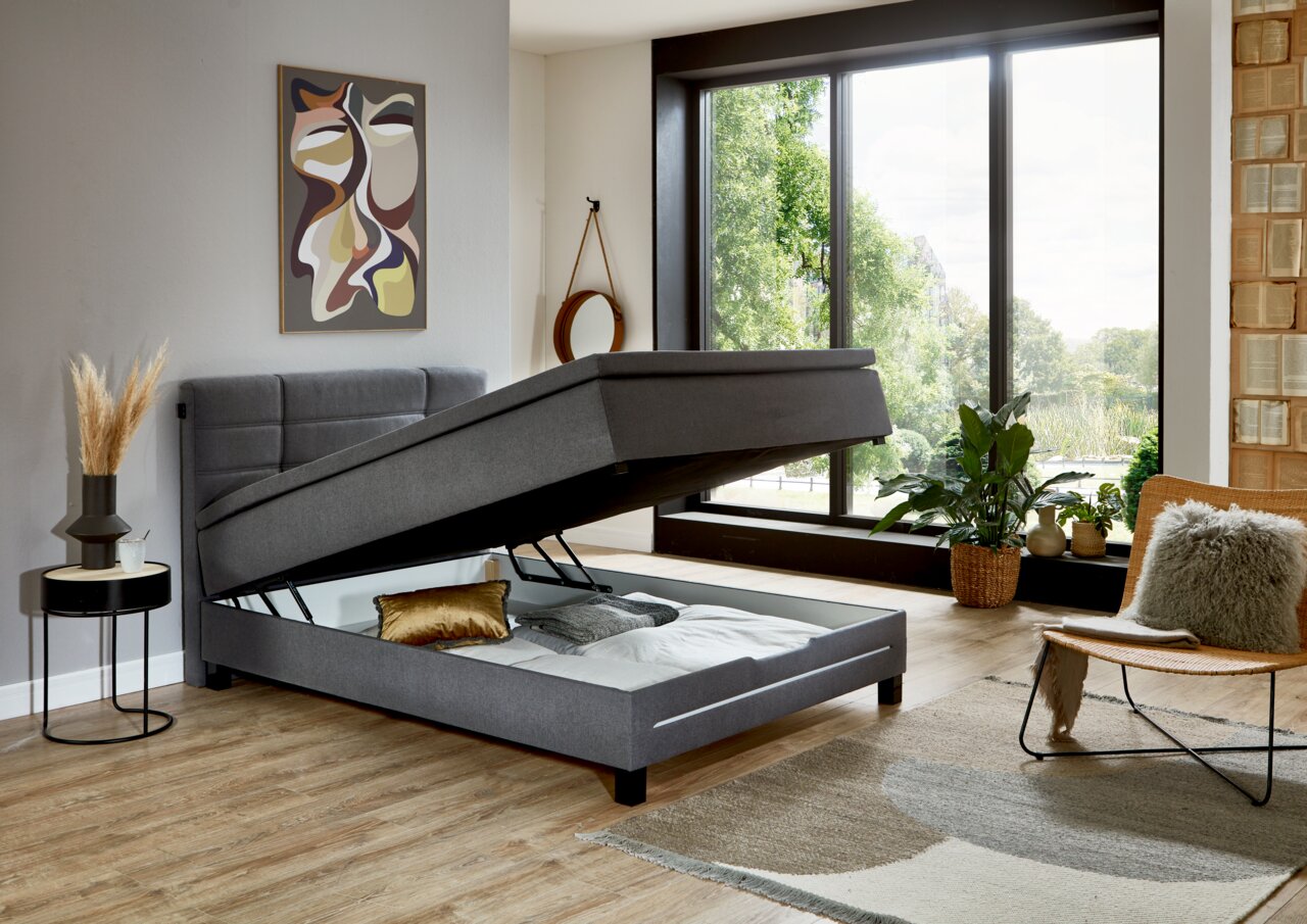 Modernes Boxspringbett in einem stilvollen Schlafzimmer mit geöffneter Bettkastenfunktion, seitliche Perspektive.