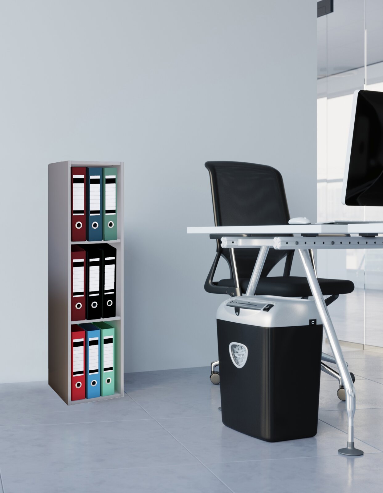 Moderner Aktenvernichter in Schwarz mit silbernem Kopf unter einem Büroschreibtisch, seitliche Perspektive im Büro neben einem Regal mit farbigen Ordnern