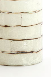 Nahaufnahme eines Teelichthalters mit einem strukturierten, cremefarbenen Keramikdesign in Ziegeloptik.