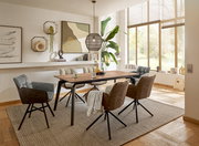 Moderner Esstisch aus Holz mit schwarzen Metallbeinen, umgeben von gepolsterten Stühlen in einem hellen, stilvoll eingerichteten Raum mit großen Fenstern und dekorativen Elementen. Perspektive von der Seite.