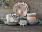 Kombiservice 16-tlg mit bunten Mustern, bestehend aus Tellern, Tassen und Schalen, auf rustikalem Holztisch aus seitlicher Perspektive.