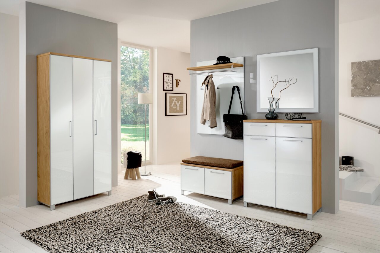 VOSS Garderobepaneel SANTINA Moderne garderobe-inrichting met een witte schoenenkast met hoogglansafwerking, een spiegel en een garderobepaneel in een lichte ruimte, gezien vanuit de zijkant.