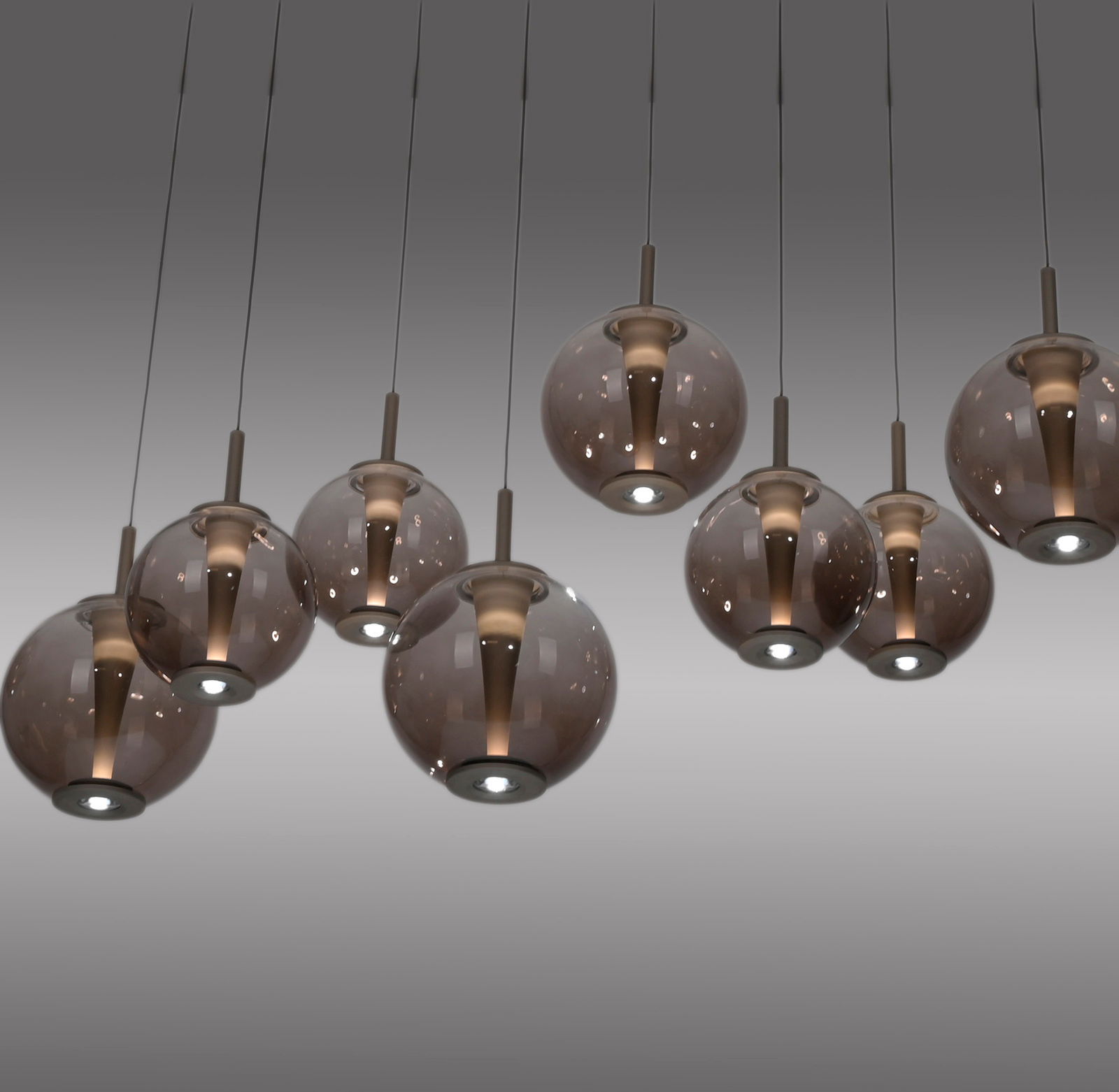 Moderne LED-Pendelleuchte mit mehreren rauchgrauen Glaskugeln, von unten betrachtet.